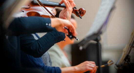 Närbild av en violinist som spelar med stråke framför notställ