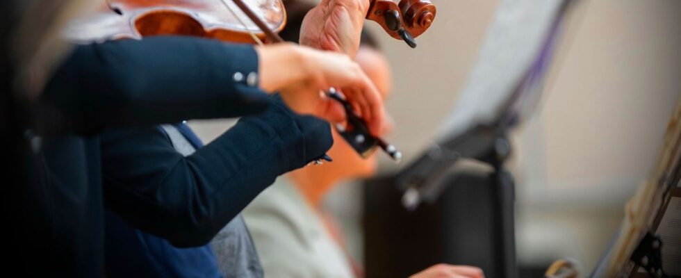 Närbild av en violinist som spelar med stråke framför notställ