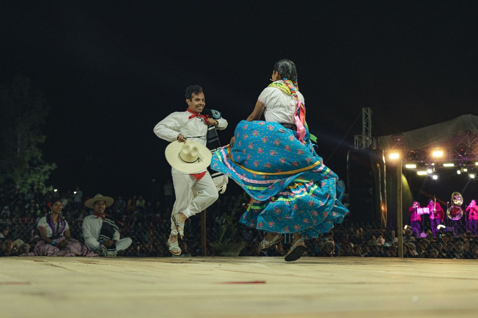 Folkdansare i färgstarka dräkter dansar på en upplyst scen